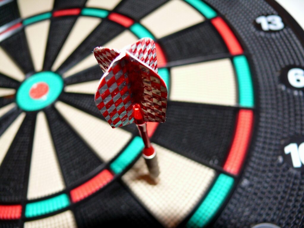 Drei Dartpfeile im Bullseye einer Dartscheibe